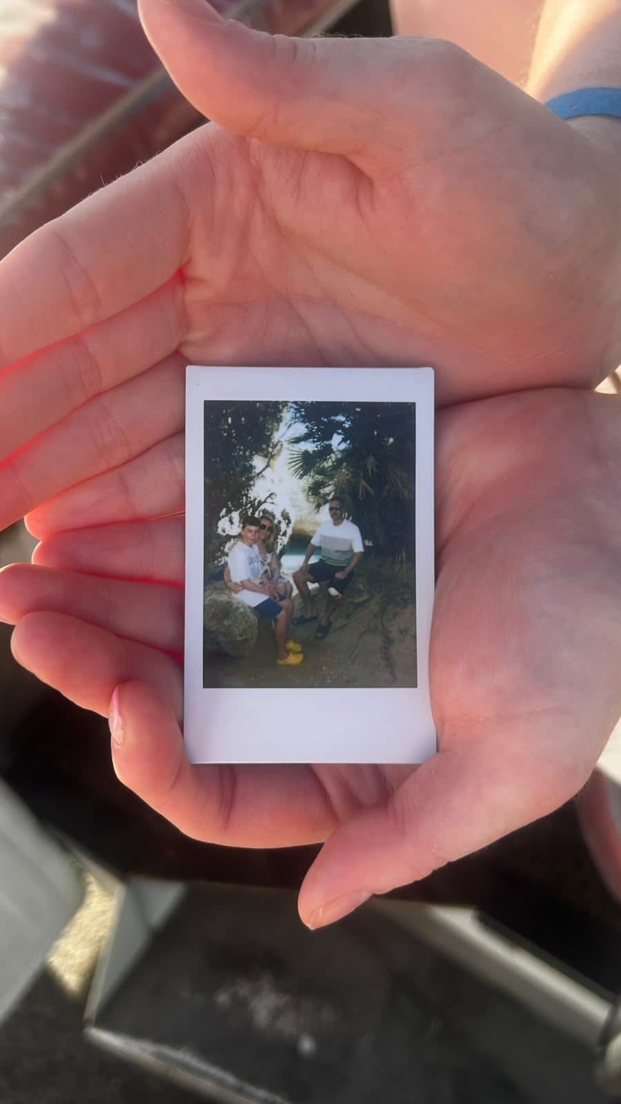 An instant print of two guests at the cove, held in the palm of a hand