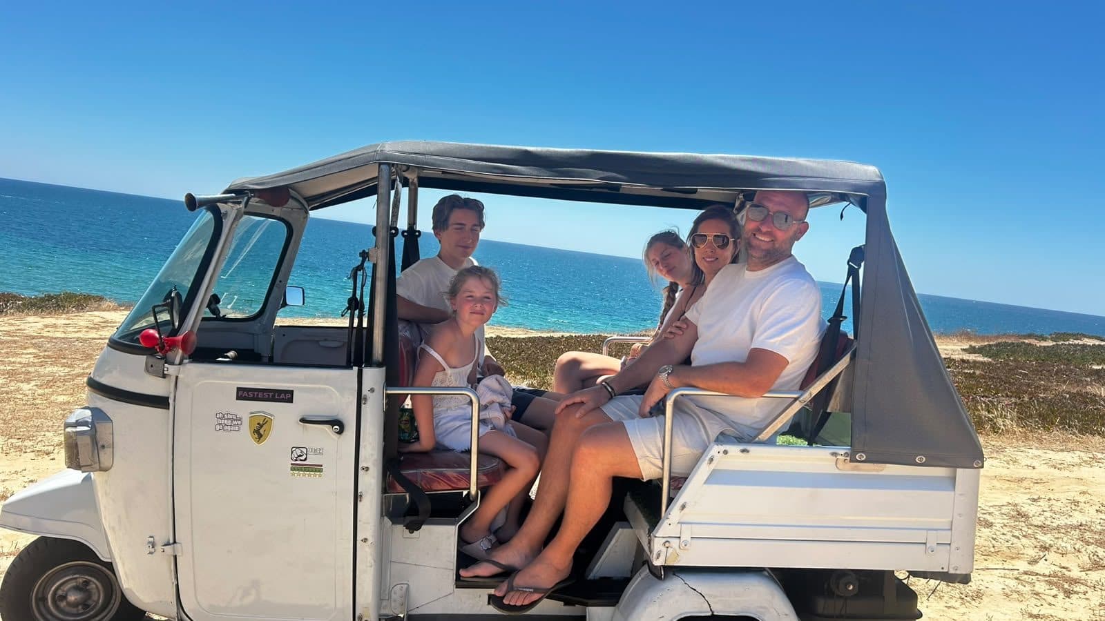 A family sitting in Tiago's tuk tuk on the sand above an Albufeira beach